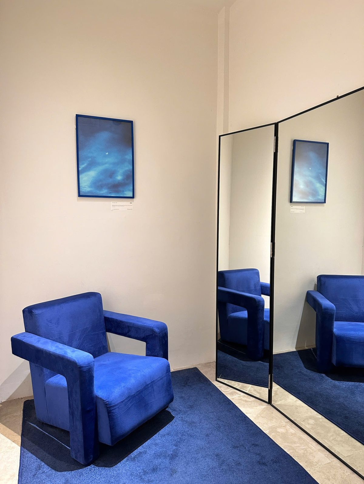 Inside the COCOSIN boutique: a blue velvet armchair, a tall mirror and blue artwork