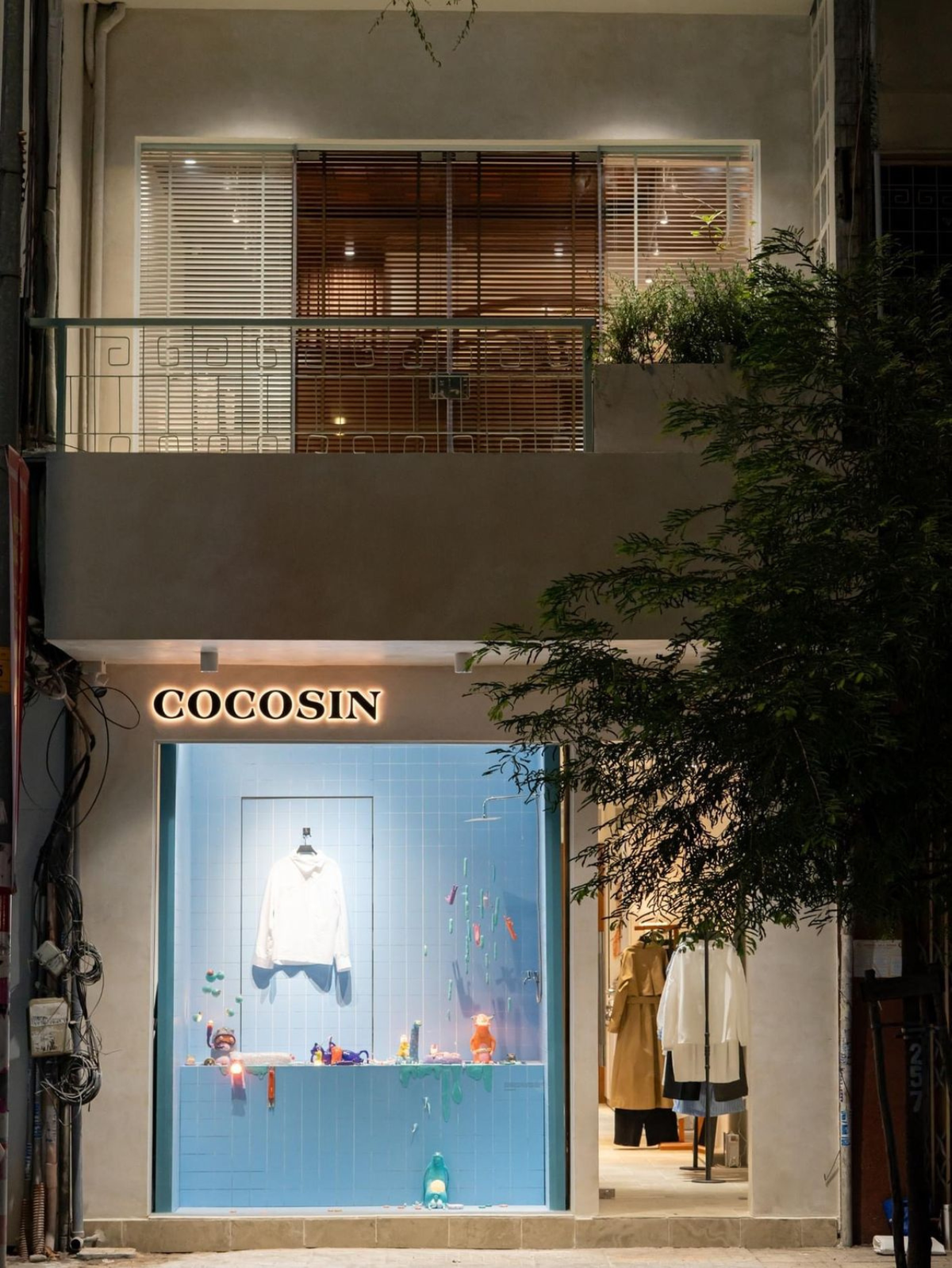 The COCOSIN boutique at night: the lit shop window under the COCOSIN sign